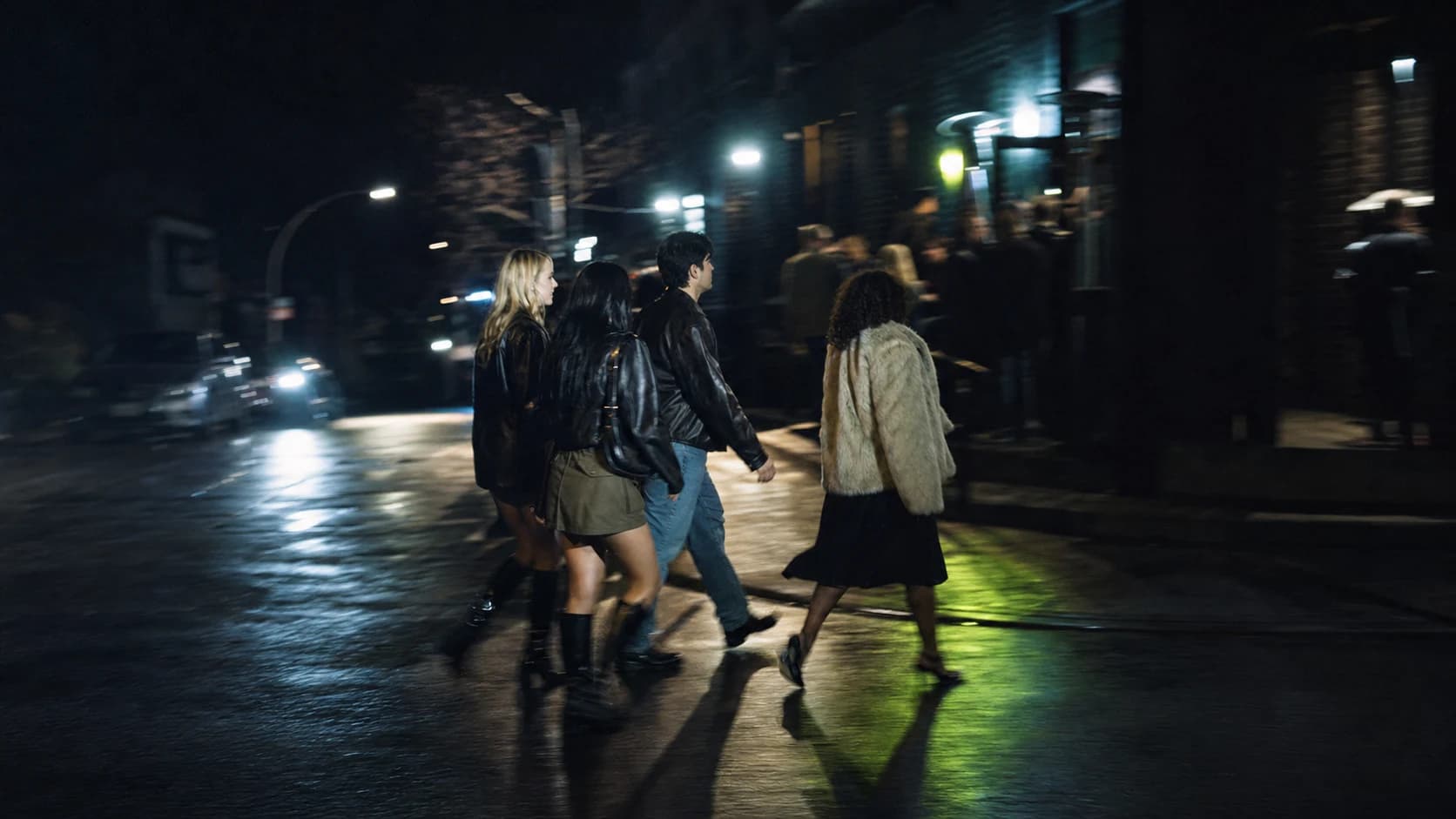 Friends crossing a wet Toronto street toward a busy venue
