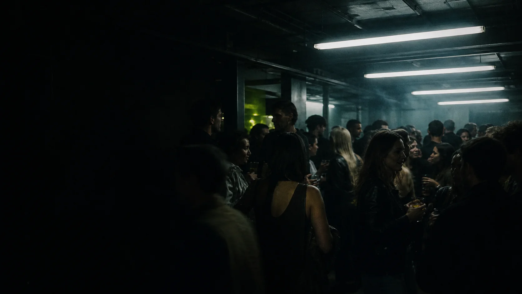 A low-lit Toronto nightlife crowd beneath fluorescent ceiling lights